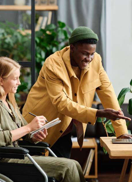 Young confident businessman pointing at laptop screen during presentation of project points to colleague making notes